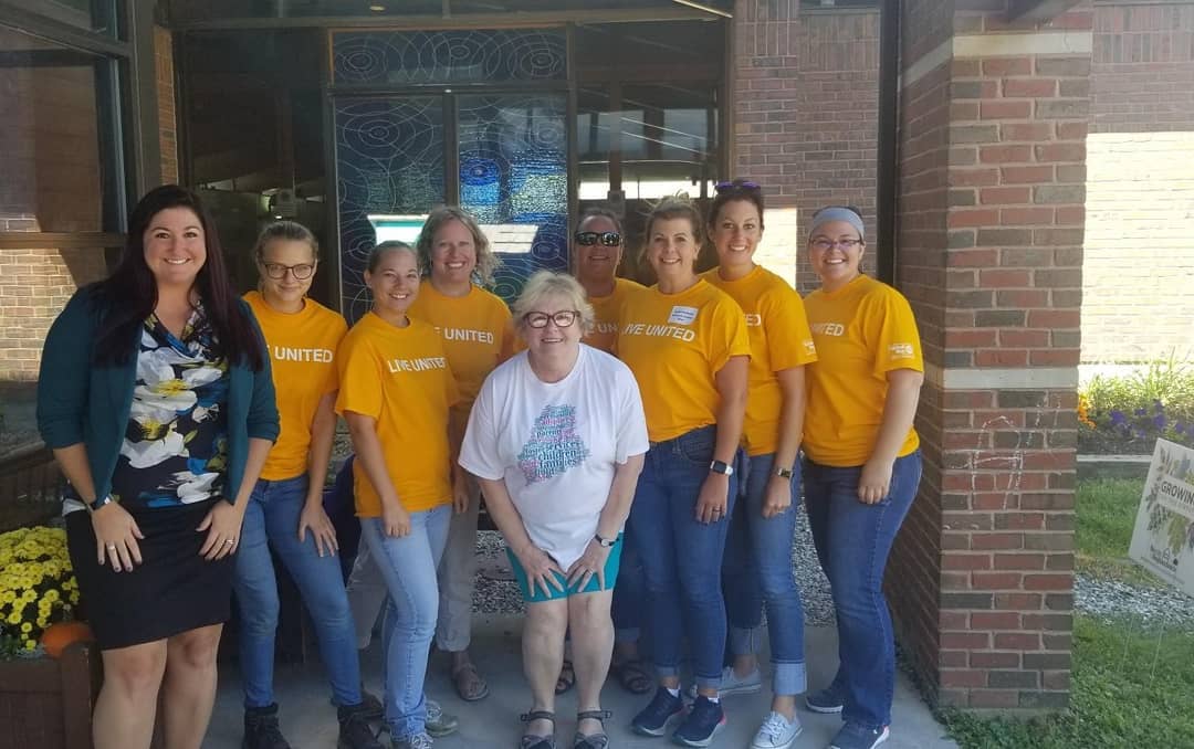 A group of Mechanics Savings volunteers pose in front of the YWCA of Central Maine .